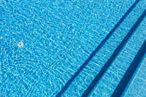 Piscine avec carrelage bleu, montrant des marches immergées et une eau claire.